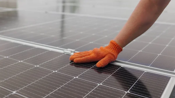 Ugjenkjennelig hanske som tørker solpanelet av støv på solskinnsdag. Nær en ung ingeniør kontrollerer han solens drift og renhet på solcellepaneler på en solnedgang.. – stockfoto