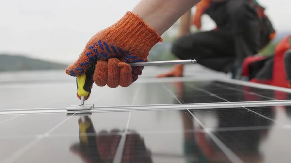 Techniciens installant des panneaux solaires sur support métallique. Travailleurs installant des panneaux solaires sur le toit d'une maison. Décryptages Installation, connexion et montage de panneaux solaires. Les travailleurs fixent des panneaux solaires — Photo
