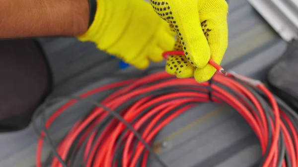 Electrician technician worker with wire stripper plier prepares the electric cable in electrical system. Electrician installing wires. A professional electrician removes electrical insulation