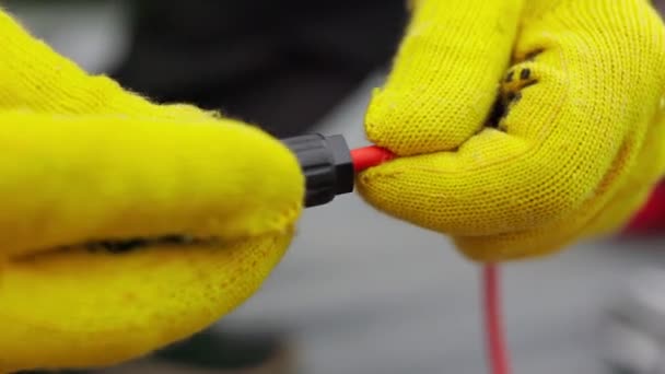 Een elektricien controleert de draden. Speciale draadverharder bij de centrale. Een elektricien in beschermende handschoenen installeert draden. Aansluiting van sojapanelen — Stockvideo