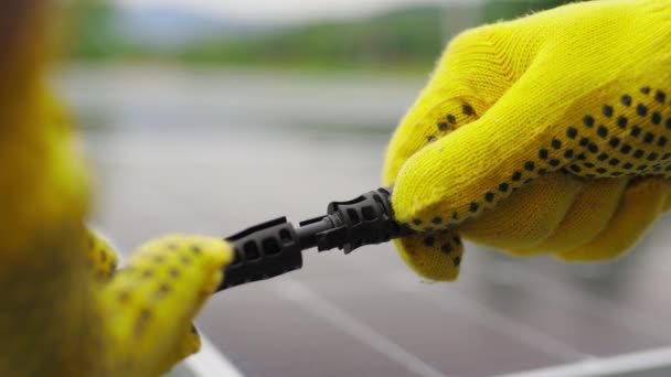 Equipamentos das estações solares. Conectando fios de painéis solares em uma fazenda solar. Os engenheiros unem o sistema elétrico ao ar livre em um contexto de painéis solares. Trabalhador em luvas de proteção conecta fio — Vídeo de Stock