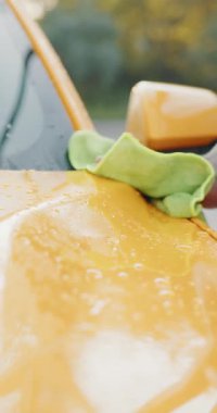 Bulanık bir arkaplan ve yeşil bir ipucuna sahip sarı bir yüzeyin soyut görüntüsü. Dikey video.