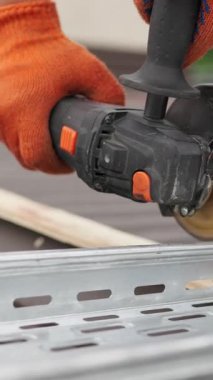 Metali kesmek için açı öğütücü kullanan, güvenlik için turuncu iş eldiveni takan birinin yakın plan fotoğrafı..