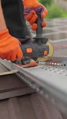 Bir işçi metal öğütmek için elektrikli bir alet kullanıyor, güvenlik eldiveni takıyor. Araç metali keserken kıvılcımlar uçuşuyor.