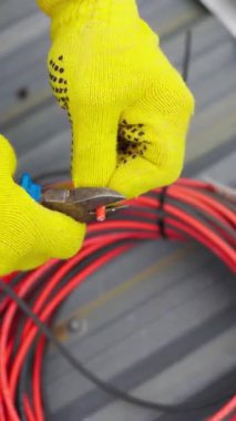 Eldivenli bir el, elektrik işini ve güvenliği vurgulayan kesik bir kabloyu tutuyor. Dikey video.