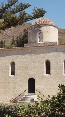 Kıbrıs 'taki antik bir kilisenin dikey çekimi, benzersiz mimarisini ve açık mavi gökyüzünün altındaki manzarasını sergiliyor..