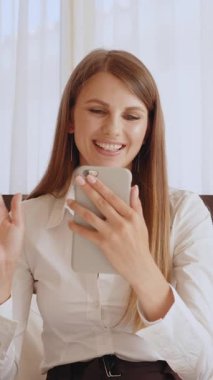 Genç bir kadın video görüşmesi sırasında elinde telefonuyla gülümsüyor..