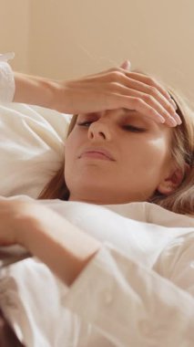 Bir kadının dikey görüntüsü, gözleri kapalı uzanmış, elleri alnında dinlenirken, muhtemelen bir rahatlama anı ya da tefekkür sırasında..