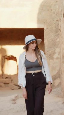 Şapka ve beyaz gömlek giyen güzel bir kadın. Dikey video.