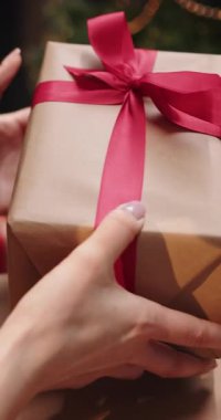 Bir el, güzel paketlenmiş kırmızı kurdeleli bir hediye tutar. Özel durumlar için mükemmeldir.