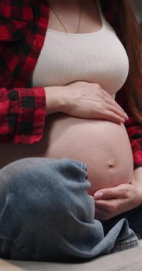 Hamile bir kadın nazikçe bebeğin karnını şişiriyor, anneliğin ve beklentilerin güzelliğini gösteriyor.