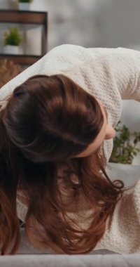 Hamile kadınların göbeğine yakın çekim. Elleri nazikçe üzerinde dinleniyor, günlük giysiler giyiyor ve yumuşak bir gülümsemeyle aşağıya bakıyor.