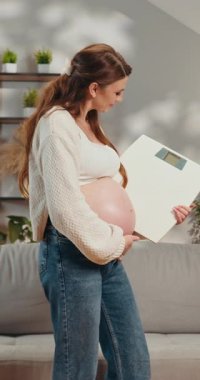 Hamile bir kadın hamilelik süresince kilo alımını izliyor, evde mutlu ve mutlu hissediyor.