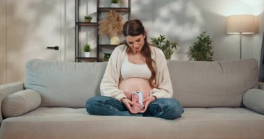 Anneler koltukta oturup, elinde akıllı bir telefonla hamile karnına ultrason görüntüsü göstererek yeni bir hayat bekliyor. Hamile Kadın Karnında Ultrason Gösteriyor