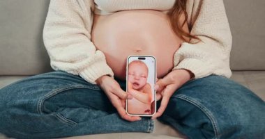 Hamile kadın koltukta oturup elinde telefonla bebek ultrasonu görüntüsü gösteriyor. Annelik ve yeni bir hayat bekliyor. Hamile Kadın Bebek Ultrasonu Gösteriyor