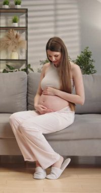 Genç bir kadın rahat bir kafede oturmuş kahvesini yudumlarken ve uzaktan çalışırken bilgisayar ekranına odaklanmış.