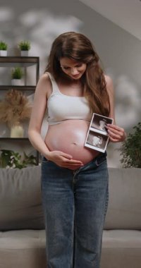 Müstakbel anne, elini karnının üzerine koyduğu sırada doğmamış bebeğinin ultrason görüntülerini gururla gösteriyor.