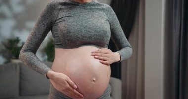 Evde müzik dinlerken kulaklık takıp karnına dokunan hamile bir kadın. Hamile Kadın Müzik Dinliyor. Hamile Kadın Müzik Dinliyor