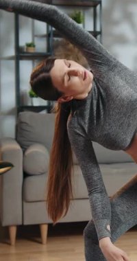 Atletizmde hamile bir kadın göbeğini nazikçe sarkıtır, yumuşak bir ifadeyle aşağı bakar, kapalı bir yerde.