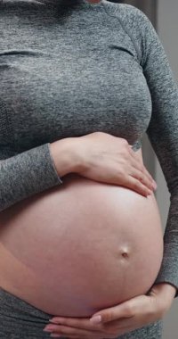 Kadınların elleri hafifçe sarmaş dolaş hamile karnına, beklenti ve annelik sevgisini göster.