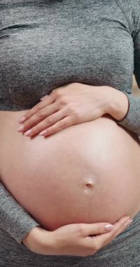 Hamile kadın kulaklık takıyor ve karnına dokunuyor. Hamilelik yolculuğu boyunca müzik dinliyor.