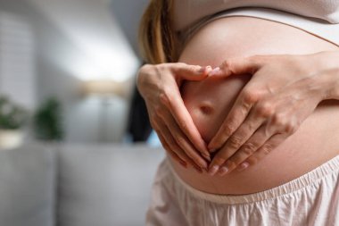 Kadınların elleri hamile karnında kalp şekli oluşturur. Yeni bir hayat için aşkı ve beklentiyi simgeler.