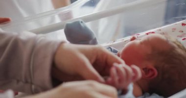 Ebeveynler yeni doğmuş bebeğe yumuşak mavi tulum giydirirler. Narin cilt ve küçük parmaklar.