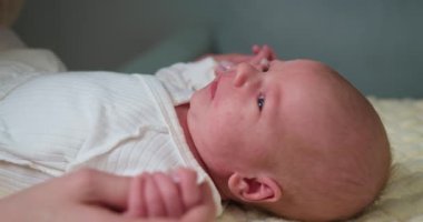 Beyaz tulum giyen, parlak gözlü ve yumuşak tenli yeni doğmuş bir bebeğin yakın plan portresi. Yenidoğan Bebek Yüzü Yaklaş