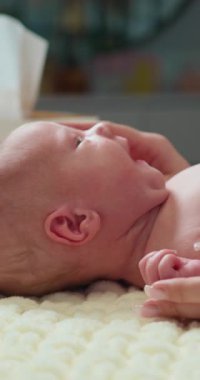 Yeni doğmuş bir bebeğin yakın plan profili narin kulak ve boynu yumuşak, dokulu bir battaniyenin üzerinde dinleniyor ve ilk yaşam anlarını yakalıyor.