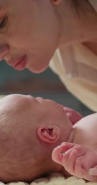 Anne, yeni doğmuş bebeğini şefkatle öpüyor. Sevgisini ve sevgisini nazikçe kucaklıyor.