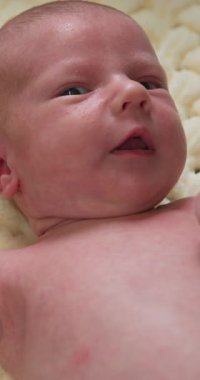 Mavi gözlü, yumuşak tenli, dokulu bir battaniyenin üzerinde dinlenen yeni doğmuş bir bebeğin yakın plan portresi.