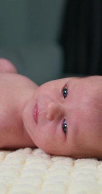 Mavi gözlü, yumuşak bir battaniyeye uzanmış yeni doğmuş bir bebeğin yakın çekimi.