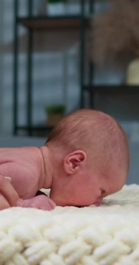 Yeni doğan bebek göbek egzersizi yapıyor yumuşak battaniye üzerinde, boyun kasları ve motor becerileri gelişiyor.