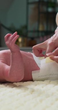 Yeni doğan bebeğin ebeveynler tarafından bebek bezi değiştirilmesi, rutin bakım sırasında küçük ayaklara ve nazik ellere odaklanılması.