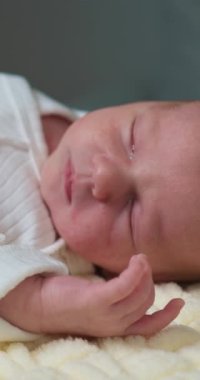 Gözleri kapalı, hassas hatları ve yumuşak cildi olan, dokulu bir battaniyenin üzerinde dinlenen yeni doğmuş bir bebeğin yakın çekimi.