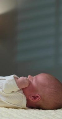 Yumuşak bir battaniyenin üzerinde mışıl mışıl uyuyan yeni doğmuş bir bebeğin yakın plan profili sakin bir ortam izlenimi veriyor.