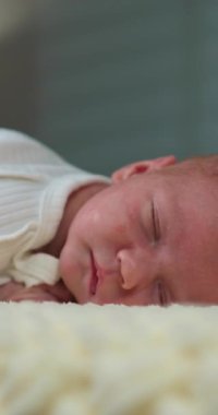 Yumuşak bir battaniyenin üzerinde mışıl mışıl uyuyan barışçıl yeni doğmuş bebeğe yakın plan.