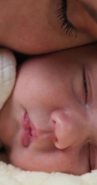 Ebeveynlerin dudaklarının yakın çekimi yeni doğmuş bebeklerin alnına nazikçe dokunuyor şefkat ve sevgi gösteriyor.