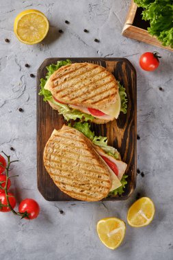 Peynirli sandviç, domates ve taze salata, tahtanın üzerinde çıtır çıtır bir kabuklu tam buğday ekmeğinden yapılmış.