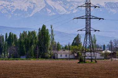 Özbekistan 'da girdap yapıyor. Köyün ve dağların arka planında tarlalar sürüldü.