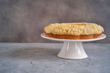 Gri arka planda beyaz, yüksek bir yerde duran güzel kokulu kek.