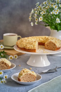 Gri arka planda beyaz, yüksek bir yerde duran güzel kokulu kek.