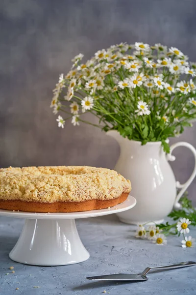 Gri arka planda beyaz, yüksek bir yerde duran güzel kokulu kek.
