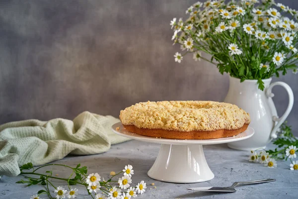 Gri arka planda beyaz, yüksek bir yerde duran güzel kokulu kek.