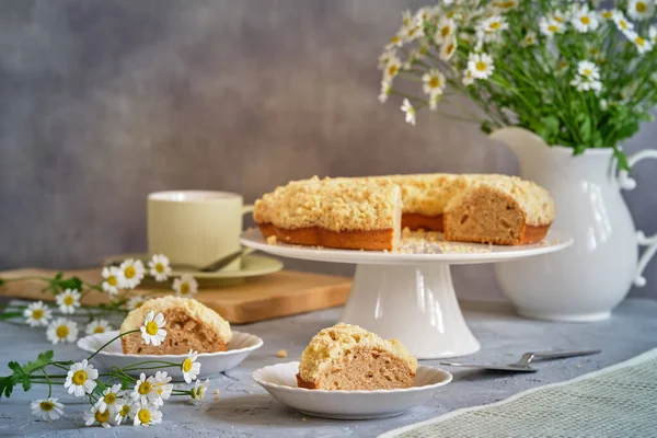 Gri arka planda beyaz, yüksek bir yerde duran güzel kokulu kek.