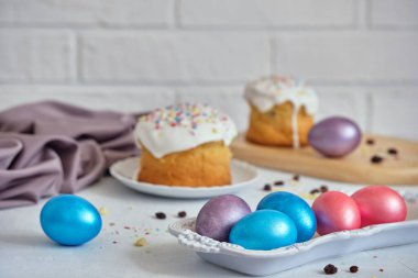Paskalya bayramı yemekleri. Paskalya pastaları ve renkli yumurtalar beyaz bir masada.