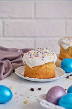 Paskalya bayramı yemekleri. Paskalya pastaları ve renkli yumurtalar beyaz bir masada.