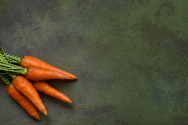Taze ve sulu taze havuç, arka planında yapraklar olan eski sıva, yakın plan.