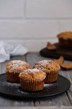Lezzetli, nazik ve mis kokulu mafinler. Eski ahşap masada siyah bir tabakta donmuş erik.