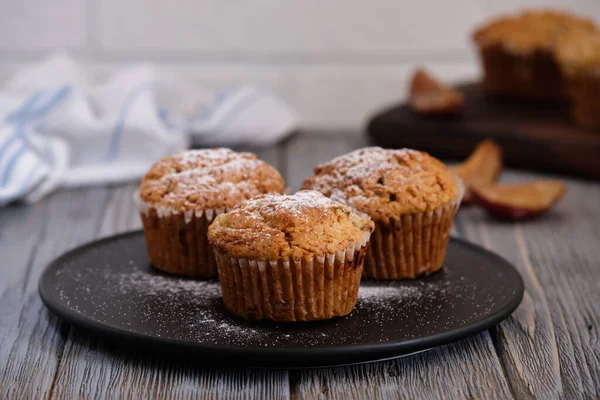Lezzetli, nazik ve mis kokulu mafinler. Eski ahşap masada siyah bir tabakta donmuş erik.